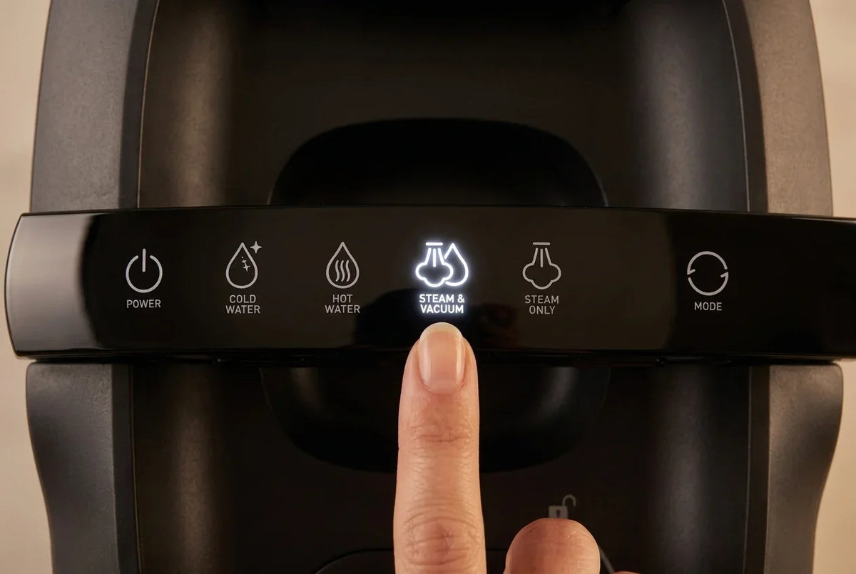 Vinger die de 'Steam & Vacuum' knop van een stoomreiniger indrukt